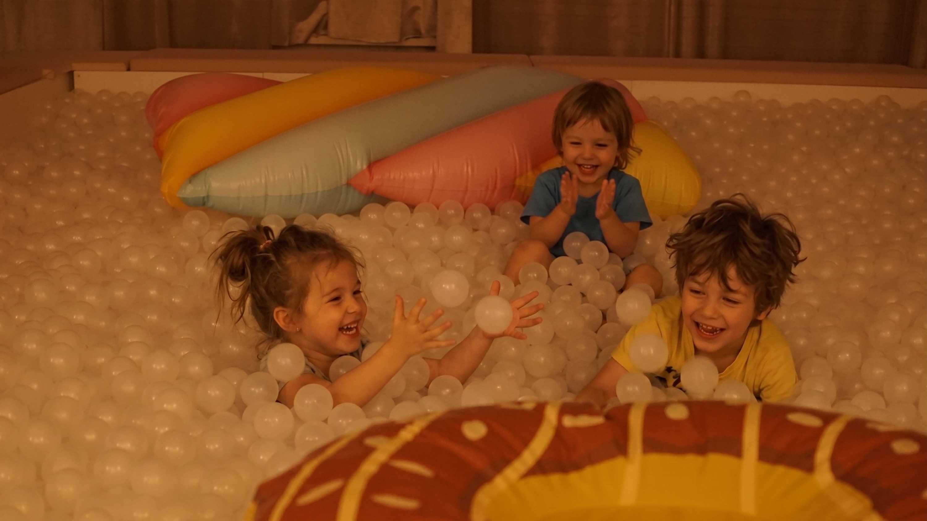 Enfants riant, piscine à balles blanches. Décor bonbons géants, Fabrique du Chocolat.