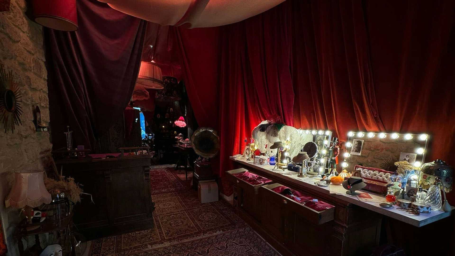 Theater dressing room, illuminated vanity, red curtains.