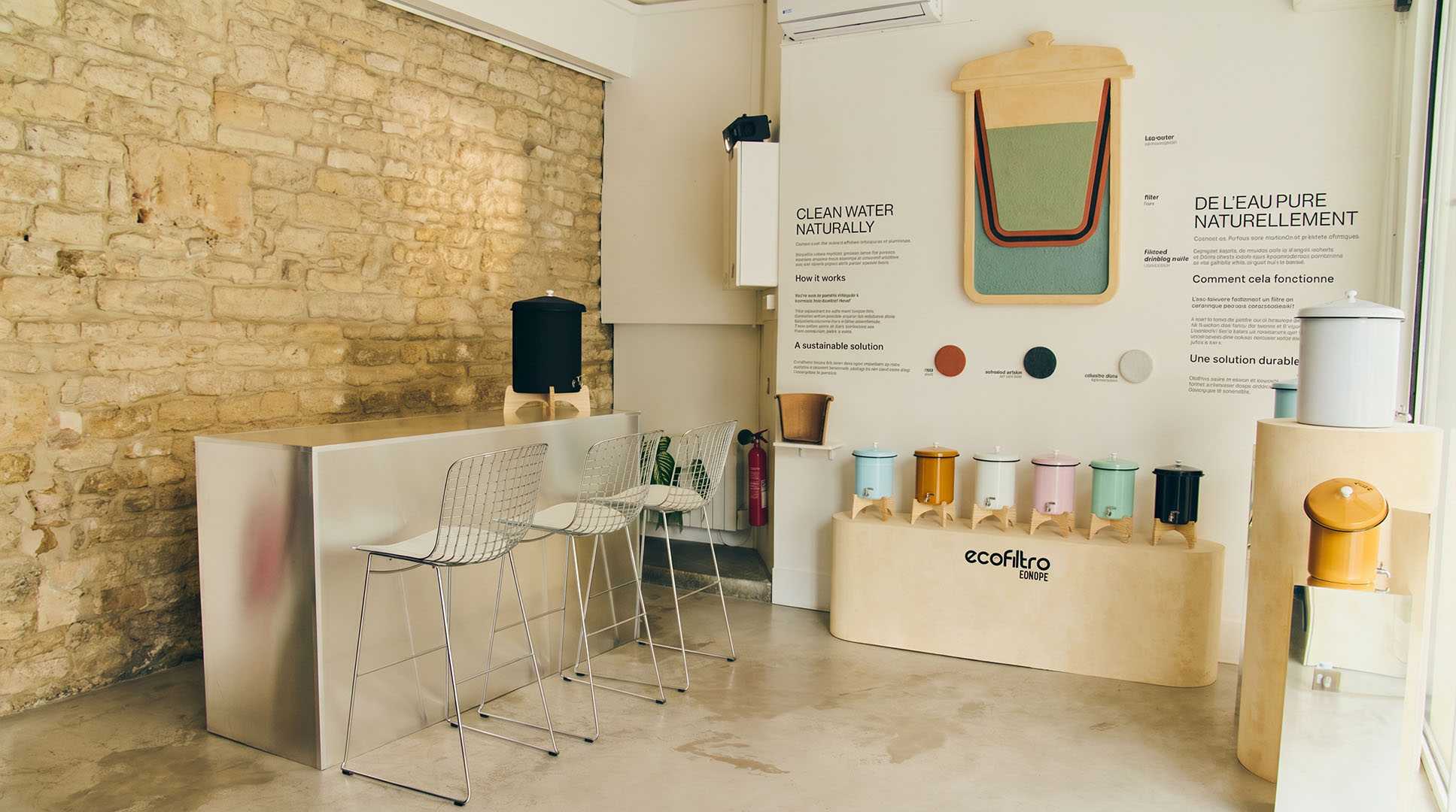 Pop-up store Ecofiltro Marais. Bar, tabourets filaires, filtres eau colorés, panneaux d'information.