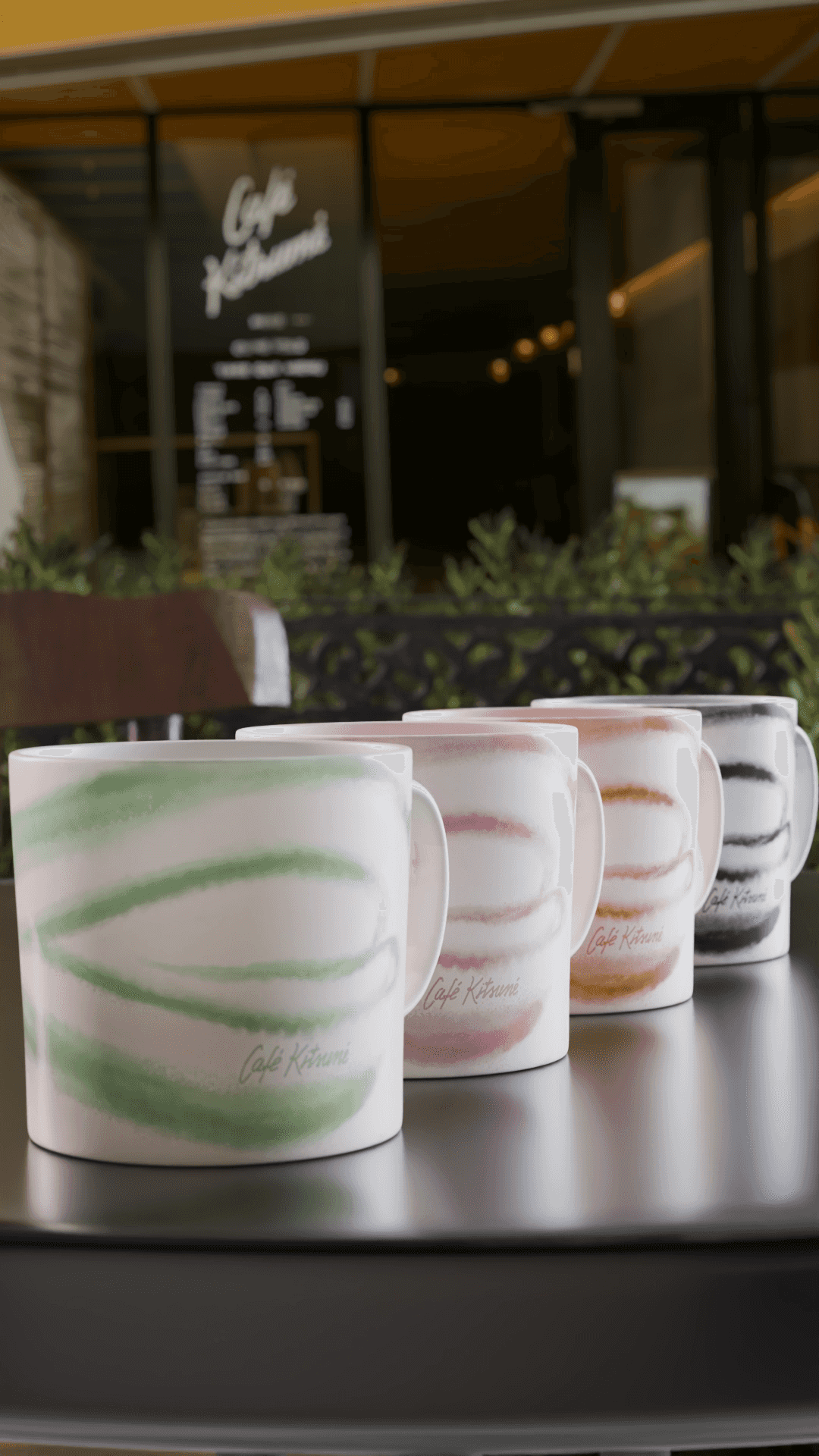 Cafe Kitsune - Multiple kitsune cup on a table with green, pink, black and brown pattern