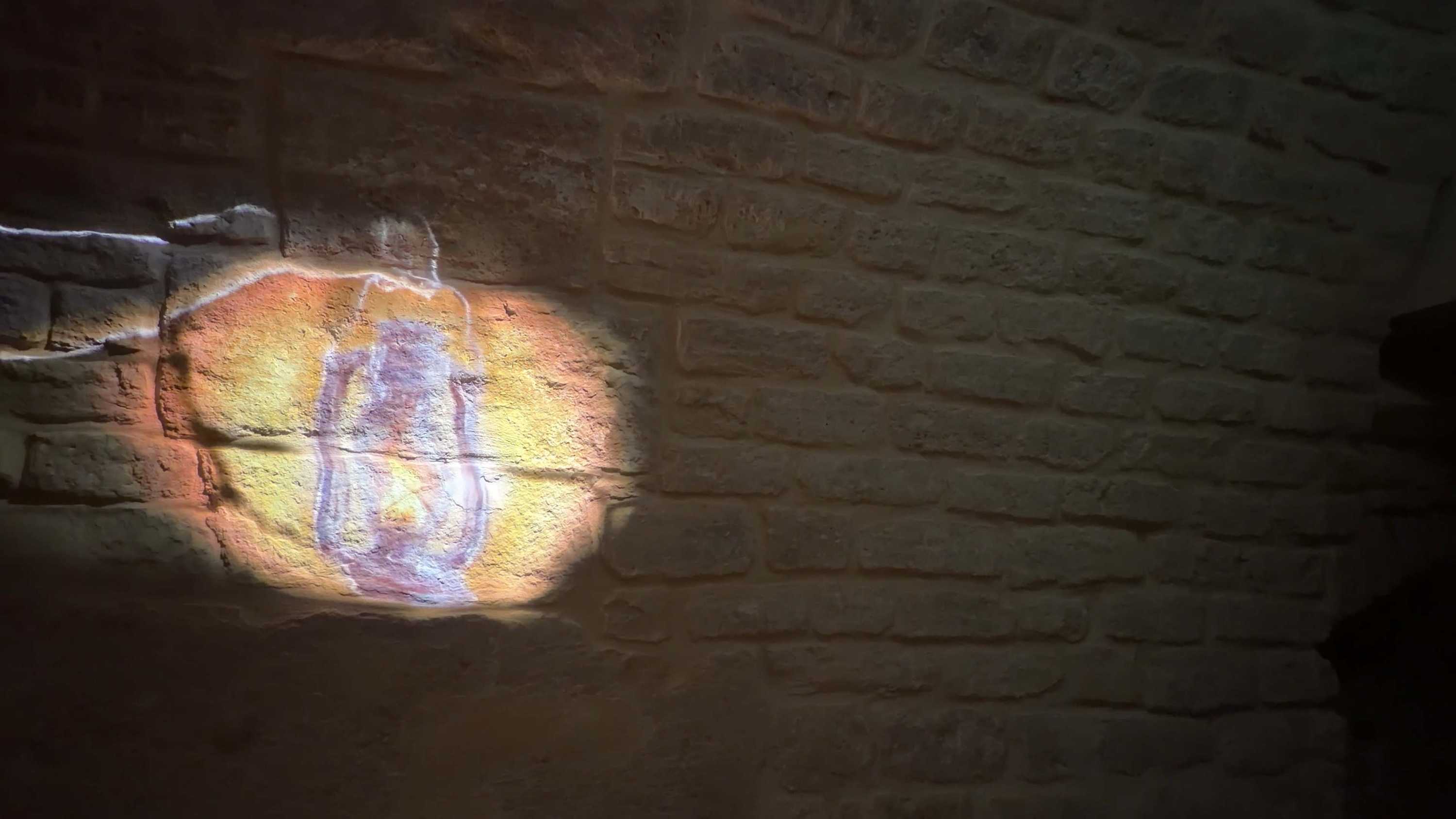 Spa Clemens projection: line-art lantern, amber light spot on brick wall.