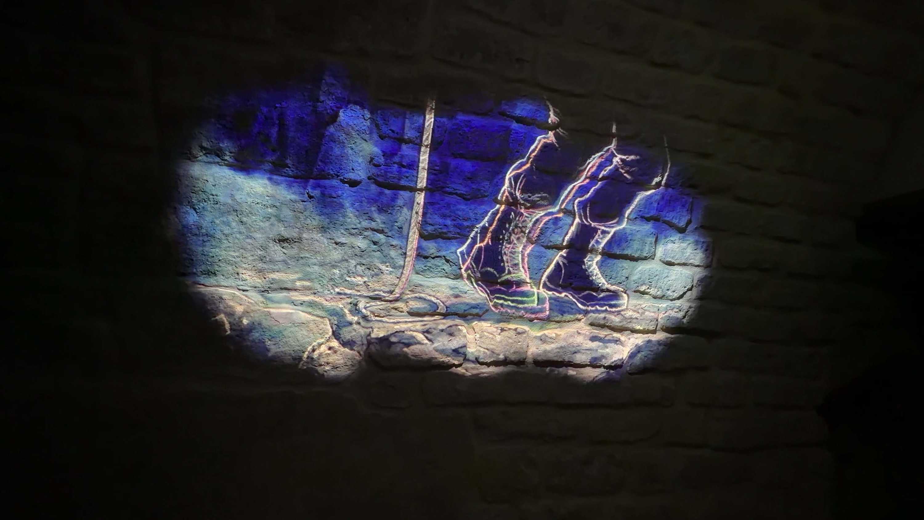 Spa Clemens projection: glowing hiker silhouette on brick wall.